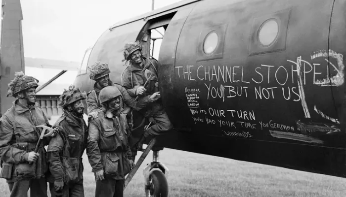 **Alt text:** *Historic photograph of Allied paratroopers beside a military aircraft before the D-Day invasion of Normandy in June 1944.*